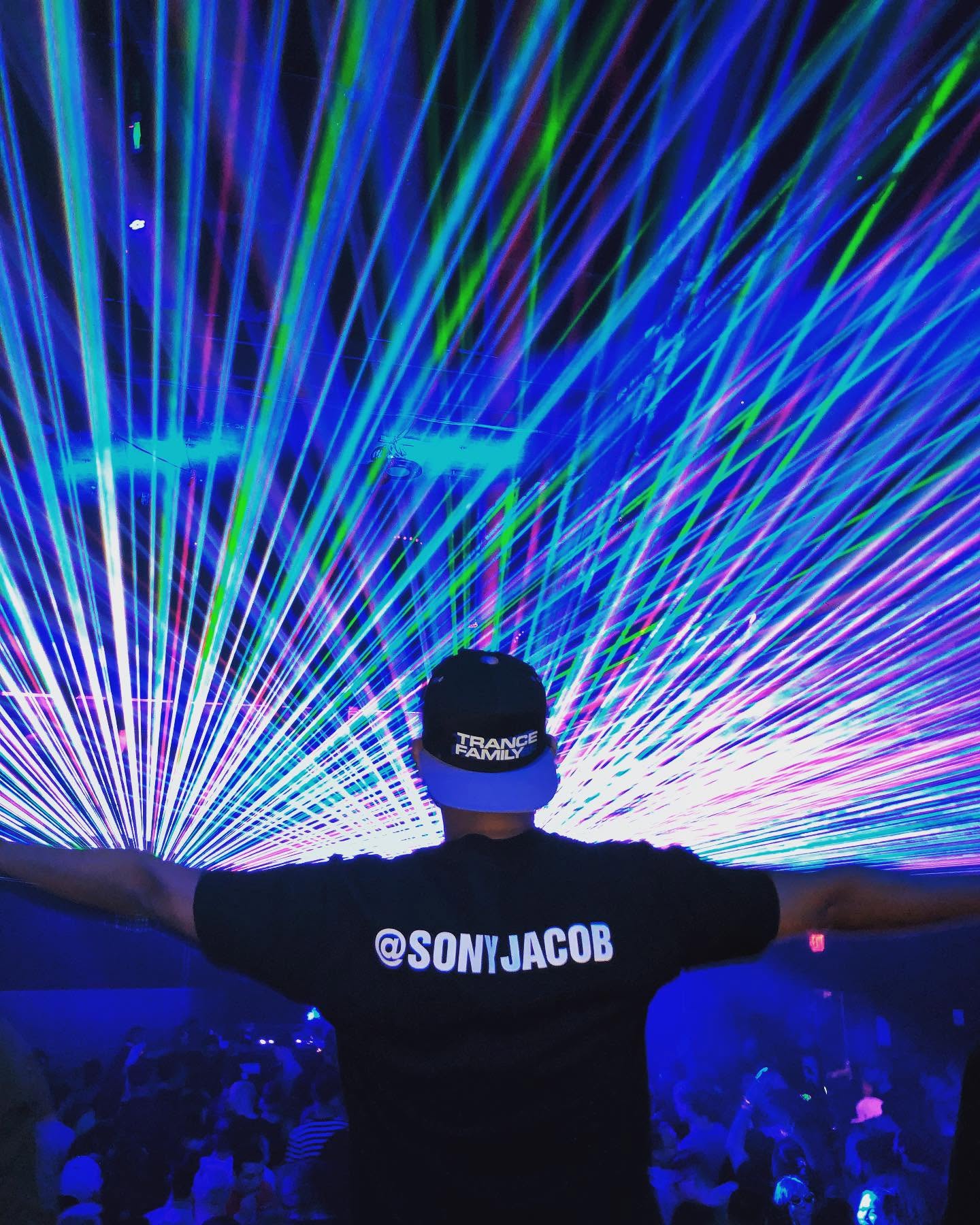 Sony Jacob with arms open in front of a canopy of blue and green lasers