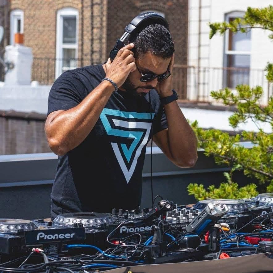 Sony Jacob concentrating on a mix with headphones on at an outdoor DJ booth